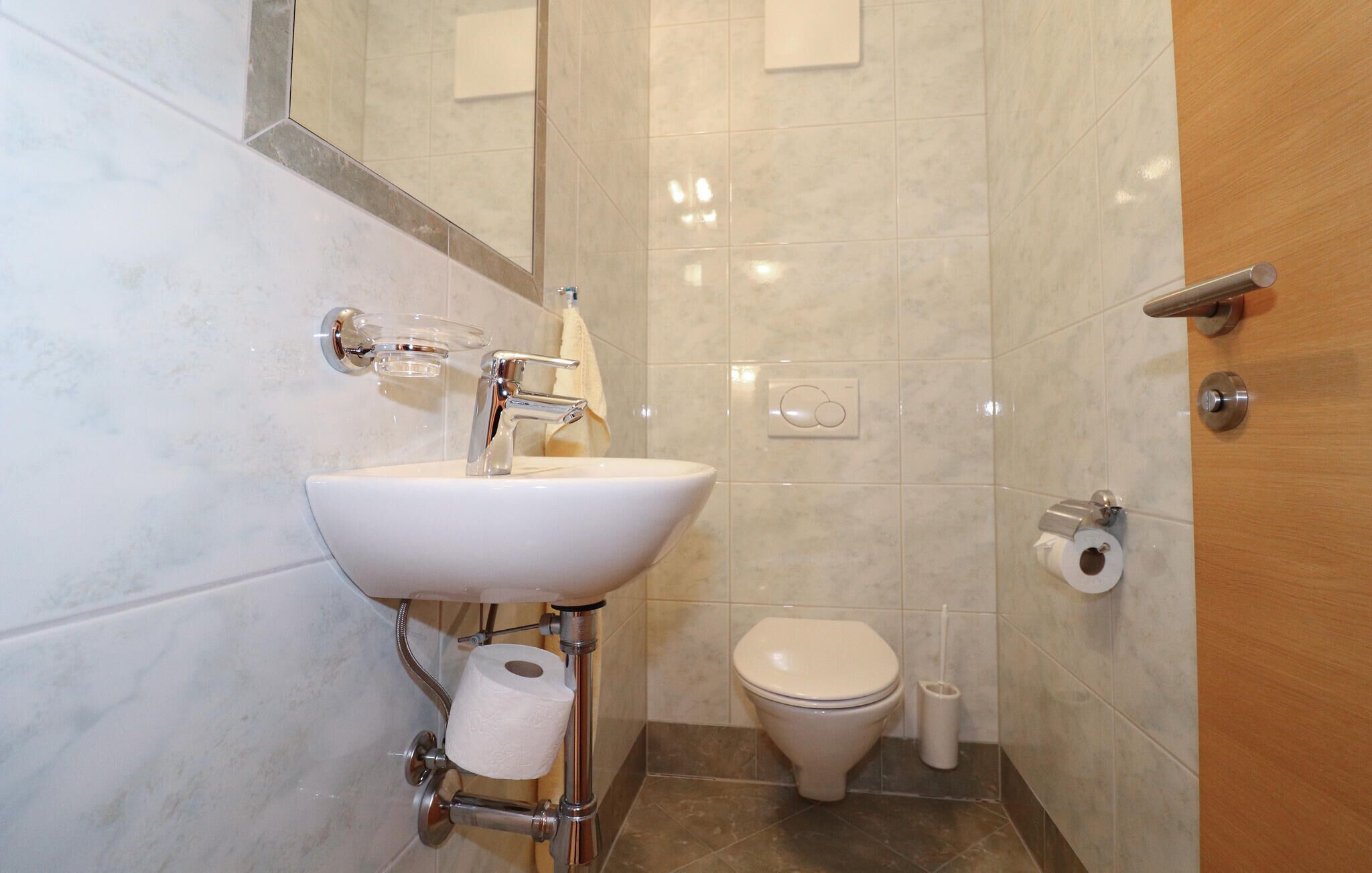 Une salle de bain avec un lavabo blanc, des toilettes et un miroir.