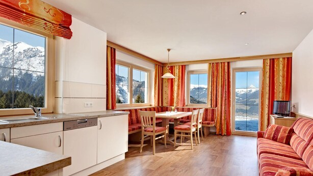 Cozinha moderna com área de jantar, janelas amplas com vista para as montanhas e uma sala de estar aconchegante.