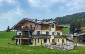 A large two-story house with multiple balconies, a stone foundation, and a hillside backdrop. - Beautiful apartment in Hollersbach with WiFi (Hollersbach)