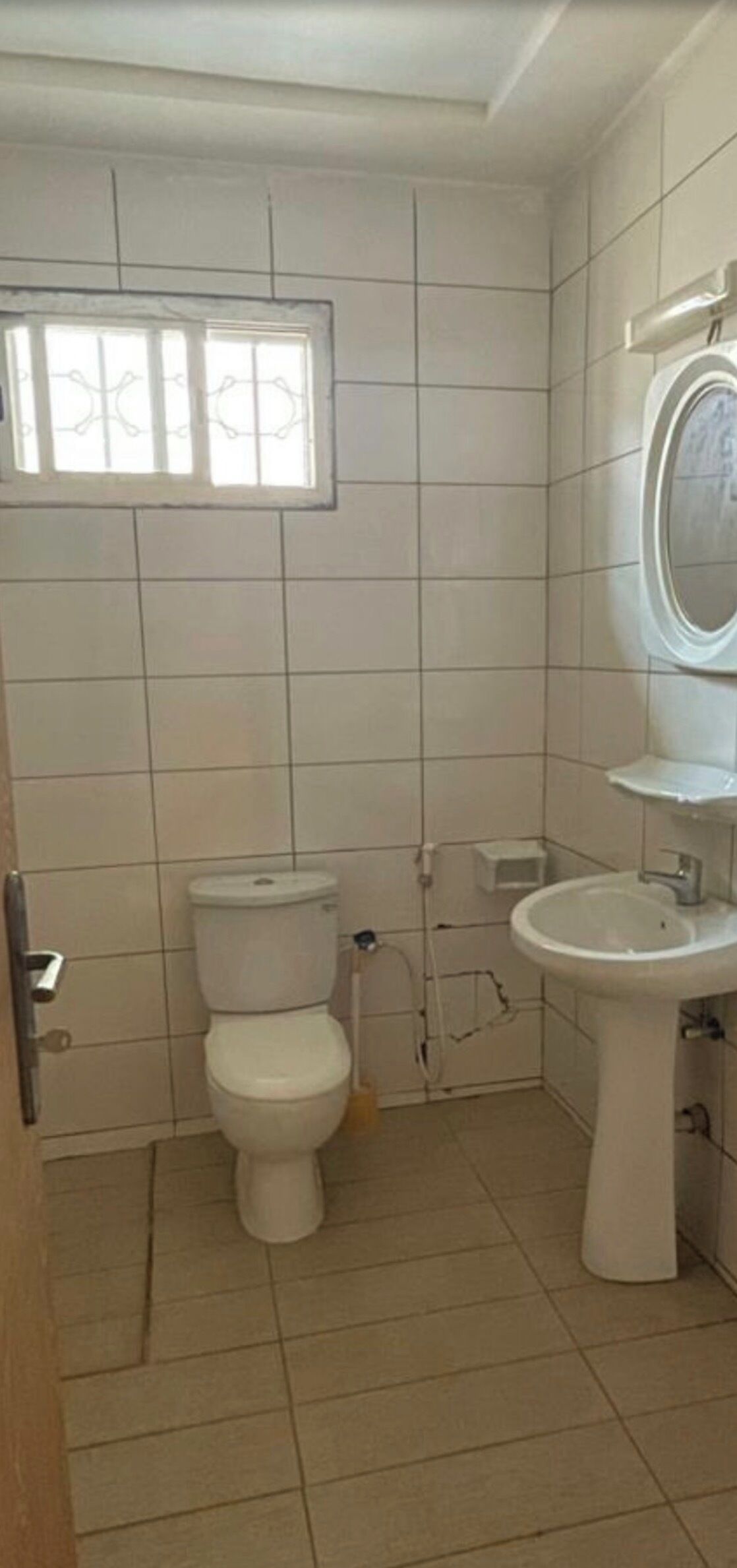 A small bathroom with a toilet, sink, and window.
