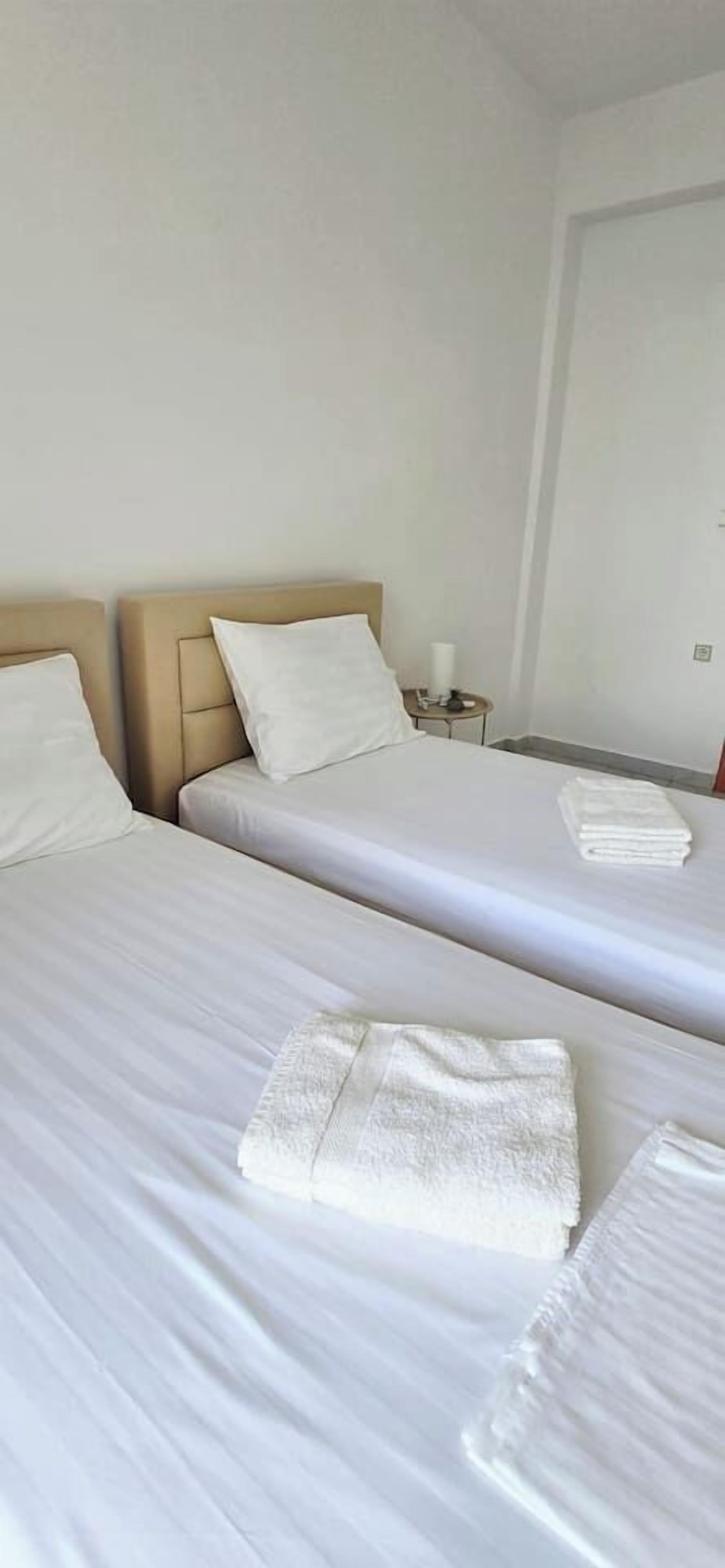 A hotel room with two beds, each with a pillow and a folded towel.