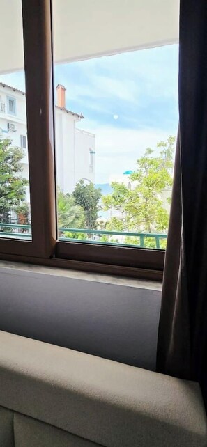 Ein Fenster mit Blick auf Gebäude und Grünflächen.