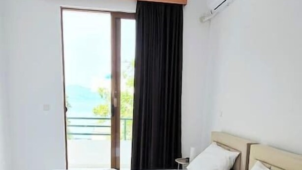 Une chambre d’hôtel avec deux lits, un balcon et vue sur la mer.
