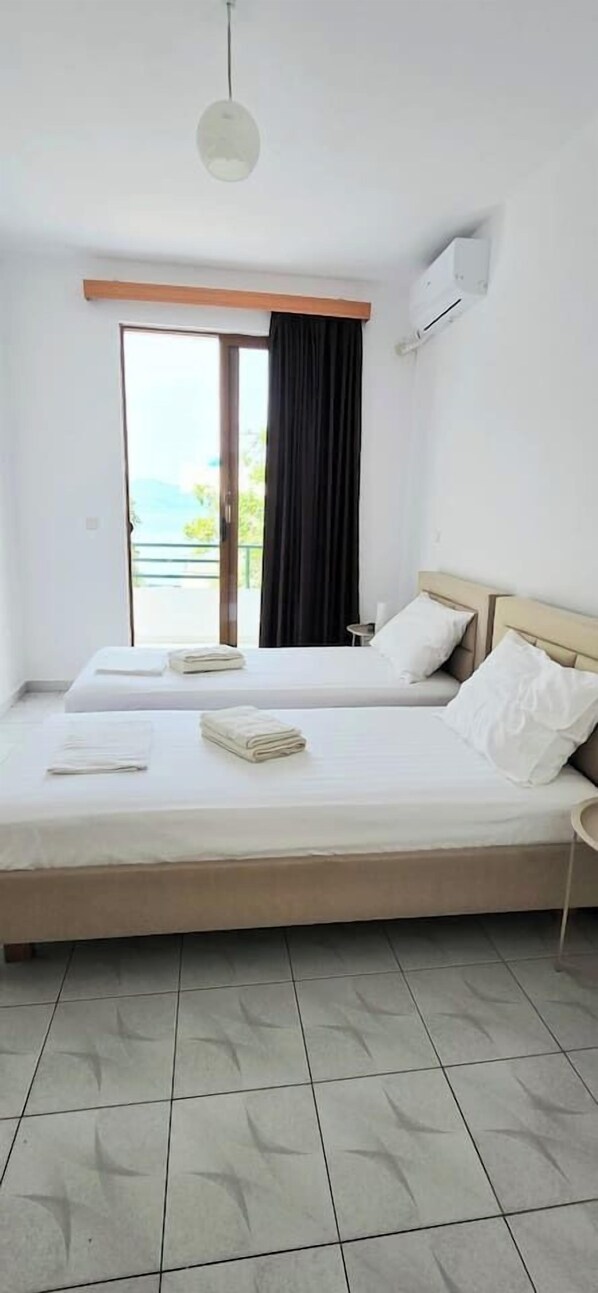 Ein Hotelzimmer mit zwei Betten, einem Balkon und Meerblick.