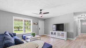 A living room with a sofa, TV, and a ceiling fan.