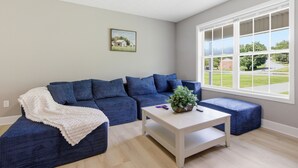 A living room with a sectional sofa, a coffee table, and a large window with a view.