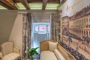 Ein Zimmer mit großem Fenster, einem Vintage-Fernseher, einer Couch und einer Wand mit einer historischen Wandmalerei.