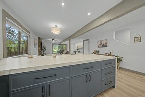 A spacious kitchen with a marble countertop, grey cabinetry, and recessed lighting.