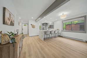 A modern kitchen with a marble island, bar stools, and a large window.