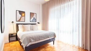 A modern bedroom with a bed, nightstands, a lamp, and two wall-mounted artworks. - Stylish 3BR in Central Porto w/ AC by LovelyStay (Porto)