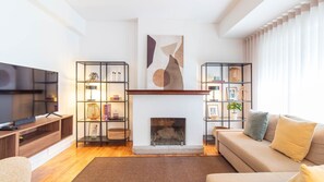 A modern living room with a fireplace, a television, and bookshelves. - Stylish 3BR in Central Porto w/ AC by LovelyStay (Porto)