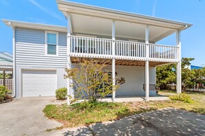 Ein zweigeschossiges Haus mit überdachter Veranda, Garage und kleinem Garten.