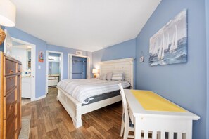 Ein Schlafzimmer mit einem Bett, einem Schreibtisch, einem Stuhl und einem Bild an der Wand.