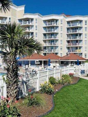 A multi-story hotel with balconies, a swimming pool, and a well-maintained garden. - Seascape - St. Regis condo #1205 (North Topsail Beach)