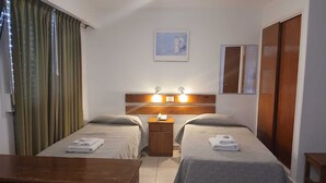 A hotel room with two beds, a wooden dresser, a nightstand with a lamp, and a painting on the wall. - El Mirador (Villa Carlos Paz)