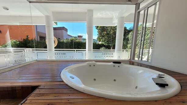 A hot tub on a wooden deck with glass railings, a clear view of the surrounding area, and a modern architectural style. - El Mirador (Villa Carlos Paz)