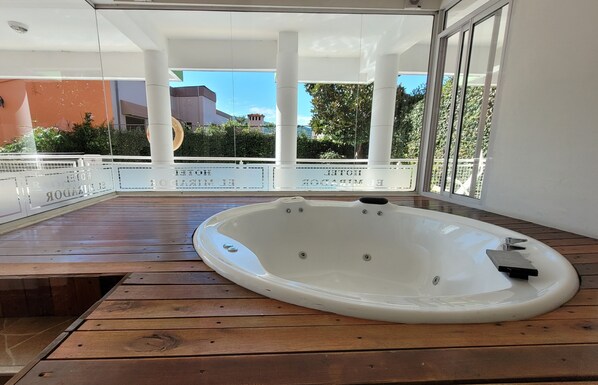 A hot tub on a wooden deck with glass railings, a clear view of the surrounding area, and a modern architectural style. - El Mirador (Villa Carlos Paz)