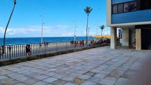 Un sendero pavimentado con barandilla, palmeras y vista al océano.