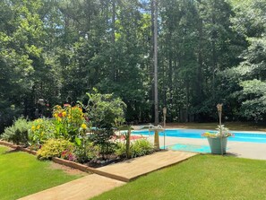 Une piscine entourée d’une végétation luxuriante et d’un jardin bien entretenu.