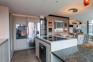 A modern kitchen with a central island, stainless steel appliances, and a view of the cityscape. - Luminar Aurelia suite (London)