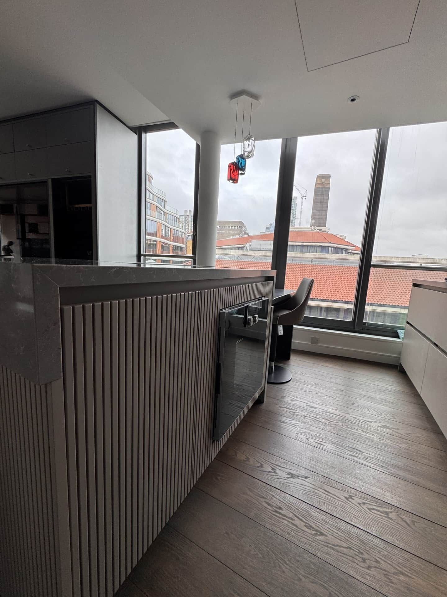 A modern kitchen with a large window, a built-in microwave, and a view of the cityscape.