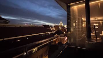 Un edificio moderno con una grande facciata vetrata, vista sullo skyline cittadino e una struttura a cupola ben visibile in lontananza.