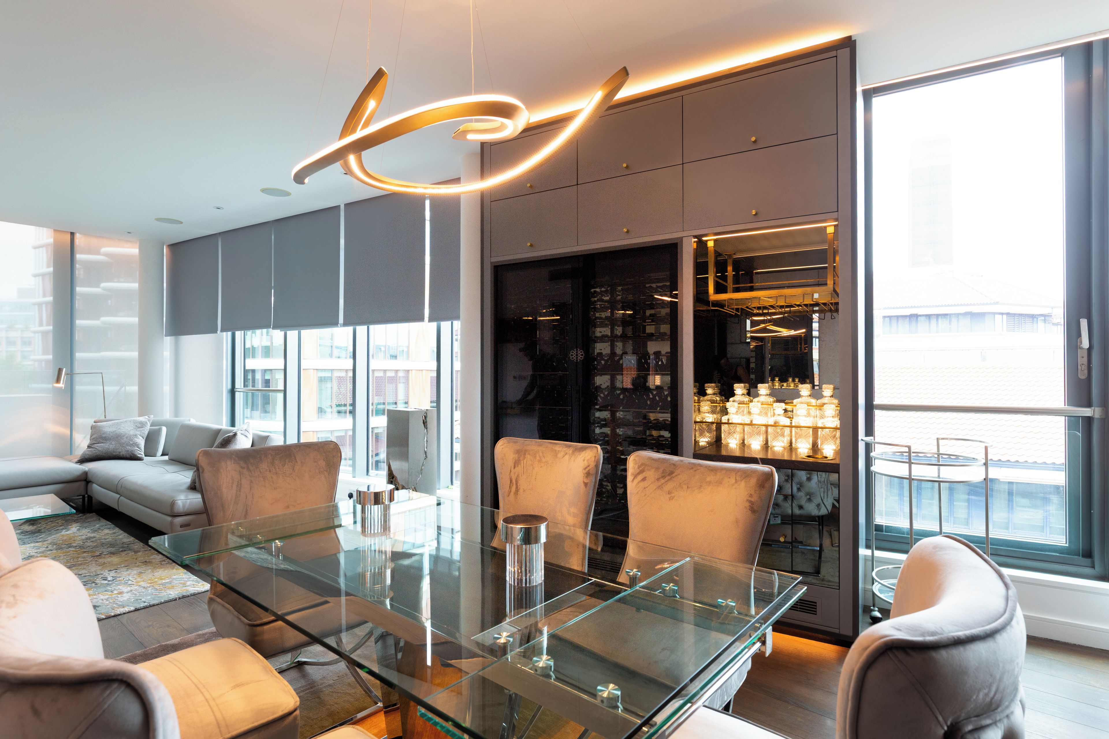 Zona pranzo moderna con tavolo in vetro, sedie imbottite e lampadario di design.