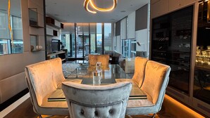 Et moderne spiseområde med et glasbord, polstrede stole og en usædvanlig rund lampe.