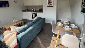Un espace de vie compact comprenant un canapé, une table à manger et un coin cuisine.