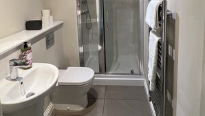 Une salle de bain moderne équipée de toilettes, d’un lavabo, d’une douche et d’une cabine de douche en verre.