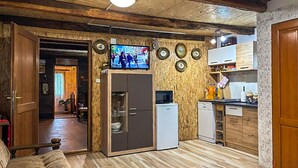 Ett kompakt bostadsutrymme med ett litet kök, en tv och ett trägolv.