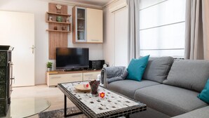 Ein Wohnzimmer mit einer Couch, einem Fernseher, einem Couchtisch und einem Schrank.