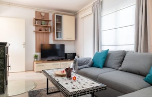 Ein Wohnzimmer mit einer Couch, einem Fernseher, einem Couchtisch und einem Schrank.
