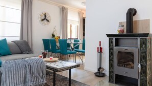 Ein Wohnzimmer mit einer Couch, einem Couchtisch, einem Kamin und einem Essbereich mit Stühlen und einem Tisch.