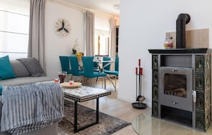 Ein Wohnzimmer mit einer Couch, einem Couchtisch, einem Kamin und einem Essbereich mit Stühlen und einem Tisch.