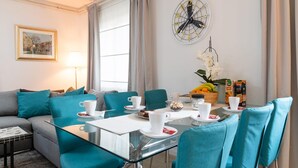 Ein modernes Hotelzimmer mit Essbereich, einer Sitzecke, einem Couchtisch und einer Wanduhr.