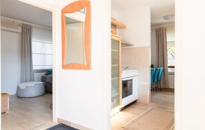 A modern kitchen with a built-in oven, a dining area with blue chairs, and a large mirror on the wall. - 3 bedroom cozy home in Tuheljske Toplice (Tuheljske Toplice)