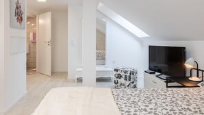 Ein modernes Schlafzimmer mit Bett, Fernseher und Schreibtisch.
