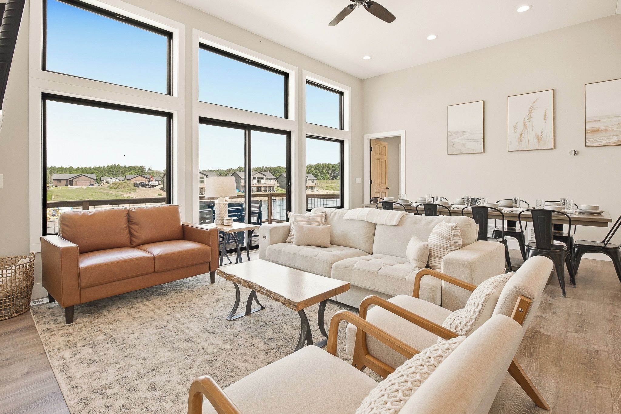 A spacious living room with large windows, a dining area, and a view of the outdoors.