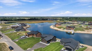 A residential area with houses near a lake, featuring a clear sky and a bridge in the distance. - NEW*Lakefront-Private Chef-Beach + Kayaks-WI Dells (New Lisbon)