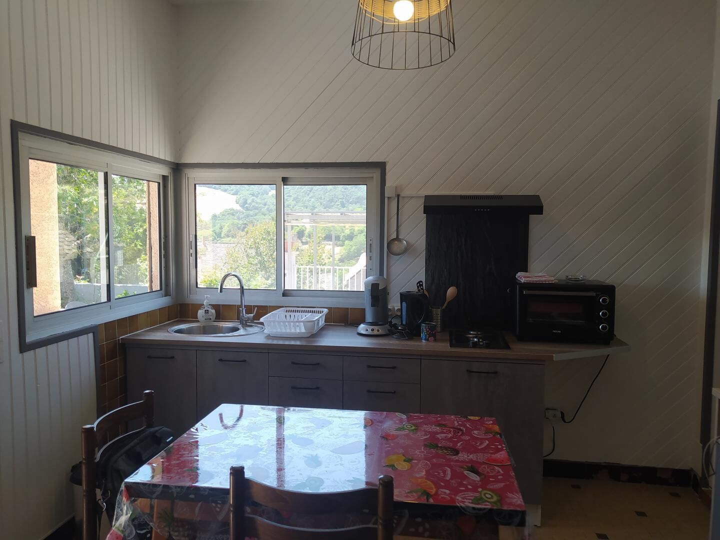 A kitchen with a window, a sink, a stove, and a table with chairs.