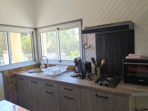 A kitchen with a window, a sink, a stove, and cabinets. - Norbert's Little House (ANTRENAS)