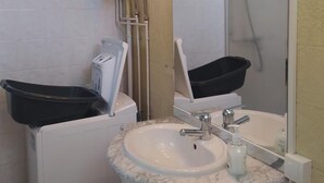 Ein Badezimmer mit einem weißen Waschbecken, einem beleuchteten Spiegel, einer schwarzen Badewanne und einer weißen Toilette.