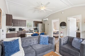 Ein modernes Wohnzimmer mit grauem Sofa, Couchtisch und Deckenventilator.