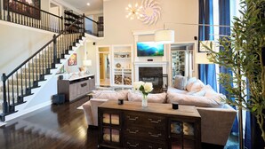 Un salón amplio con chimenea, un televisor grande y una escalera que sube a un nivel superior.