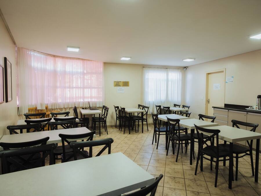 A dining area with tables and chairs, a counter, and a window with curtains.