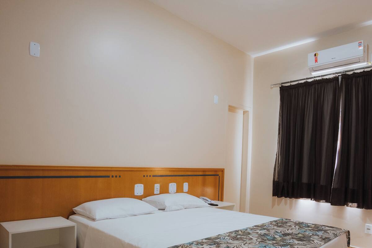 Et hotelværelse med en seng, sengeborde, et klædeskab og en aircondition.
