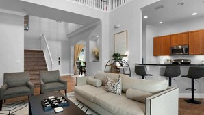 Ein modernes Wohnzimmer mit einer Couch, Sesseln und einem Couchtisch. Eine Treppe führt zu einer weiteren Ebene.