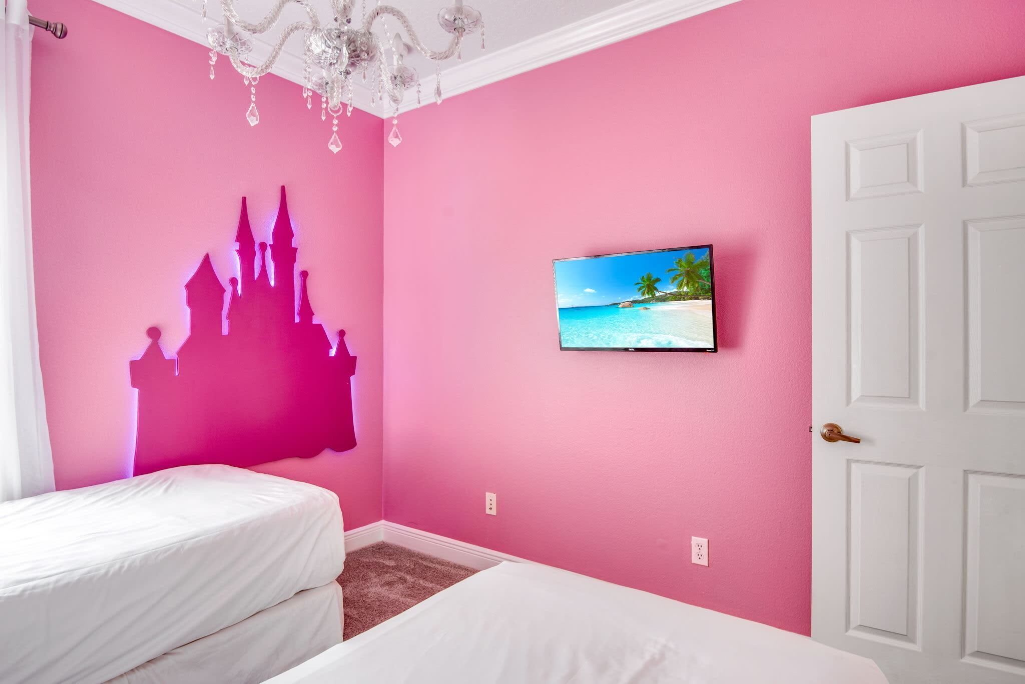 A pink room with a castle silhouette, a TV, and a white door.