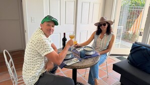 Un comedor con una mesa, sillas, una botella de vino y un vaso de jugo de naranja.